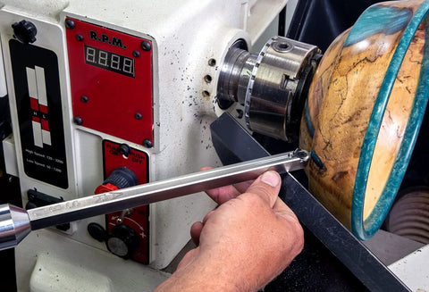 12-inch stainless steel 90° carbide turning tool for acrylic/resin, side view, Amazon brand, held near a wood lathe