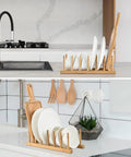 Slick Countertop Space Saver Bamboo Dish Rack And Vertical Plate Lid Organizer displaying six plates on a kitchen counter.