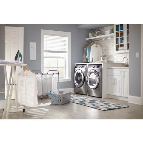 Modern laundry room with front-loading washer and dryer, ironing board, and organized countertop shelves.