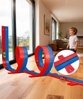 Child playing with Flexible Sixteen Point Four Foot Bendable Race Track Set with Suction Cups, blue and red, indoors on wooden floor.