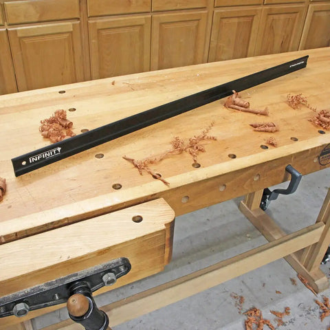 46 Inch Aluminum Precision Straight Edge For CNC And Shop Use resting on a wooden workbench, showcasing its length and slim profile.