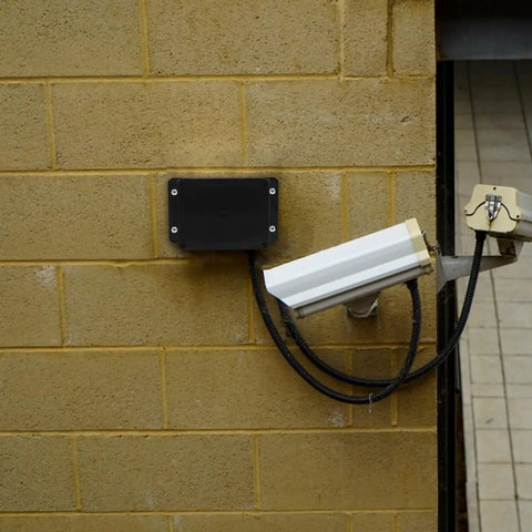 Durable Waterproof Outdoor Electrical Box Plastic Enclosure with Fixed Ear 115x90x55mm Black on brick wall next to security camera.