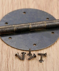 Close-up of 2 Pack 60mm Antique Bronze Round Door Butt Hinges for wood boxes and cabinets with screws on wooden surface