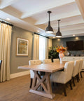 Modern dining room with wooden table, upholstered chairs, pendant lights, and large window curtains.