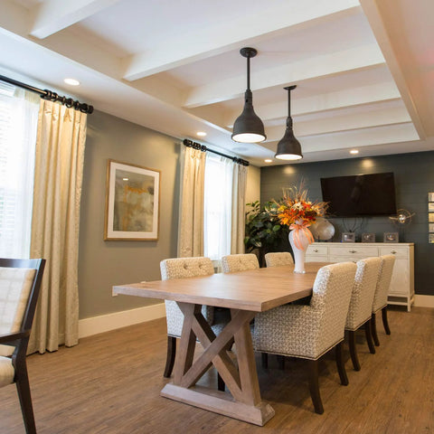 Modern dining room with wooden table, upholstered chairs, pendant lights, and large window curtains.