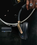 Person holding Spark NEO Wireless Guitar Headphone Amp And AI Powered Guitar Rig next to guitar with transmitter visible.