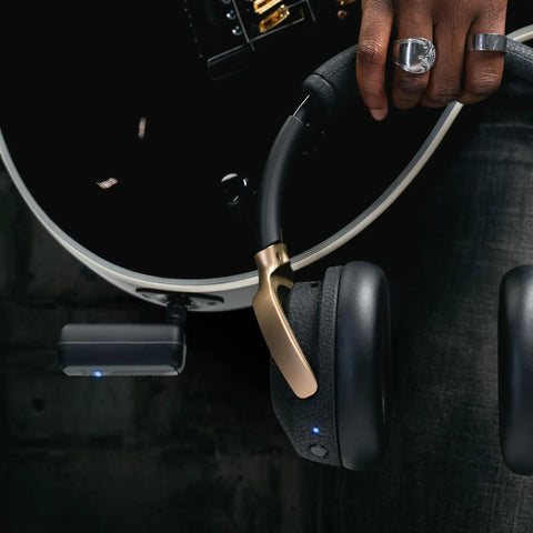 Person holding Spark NEO Wireless Guitar Headphone Amp And AI Powered Guitar Rig next to guitar with transmitter visible.