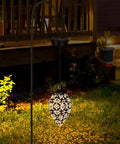 2 Pack Hanging Solar Lights With Moroccan Olive Pattern Lanterns in garden, illuminated at night for cozy ambience.