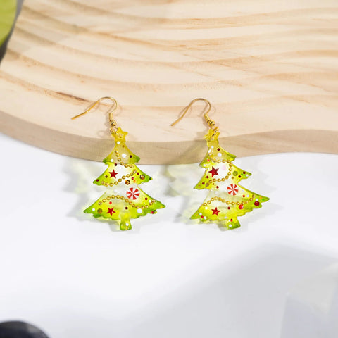 Pair of translucent yellow-green acrylic Christmas tree earrings with gold hooks and red star accents.