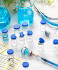 Front view of Threlaco 20 blue-cap 1ml glass vials, sterile and empty, with syringe and lab glassware in background.