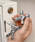 Hand holding TwinKey Multifunctional Spanner Kit With Magnetic Eight Arm Two By Four Way Spider Keys in front of radiator valve
