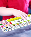 Child placing Self Adhesive Desk Nameplates Set for Primary Students Pack of 36 on desk; bright colors with alphabet, shapes.