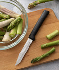 Built Tough Serrated Paring Knife Duo Featuring Premium High Carbon Stainless Steel Blades That Tear Through Tough Fruit And Veggie Skins Without A Sweat With Sleek Black Handles Pack Of Two next to chopped asparagus in a bowl.