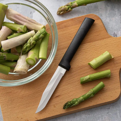 Built Tough Serrated Paring Knife Duo Featuring Premium High Carbon Stainless Steel Blades That Tear Through Tough Fruit And Veggie Skins Without A Sweat With Sleek Black Handles Pack Of Two next to chopped asparagus in a bowl.