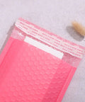 Pink Bubble Mailer Envelopes 11x15 Plus 4 Inch Padding Self Sealing Shipping Bags Thick, Shockproof Bubble Pouches on table