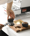 58mm Espresso Coffee Distributor Leveler With Stepless Height Adjustment placed on portafilter next to espresso machine