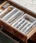 Three Compartment Utensil Tray For Kitchen Drawers With Deep Storage And Non Slip Lining Perfect For Ladles Whisks And Serving Tools Also Great For Makeup And Bathroom Storage White in a wooden kitchen drawer.