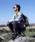 Person sitting on Heavy Duty Folding Camping Stool and Footrest Set That Unfolds in One Step Supports Up to 400 Lbs outdoors