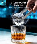 Hand using tongs to place 2" large clear cube ice into a whiskey glass, showcasing Top Counter Ice Cube Maker App Enabled Produces 110 Massive Two Inch Crystal Clear Daily Cubes For Your Home Bar With Lightning Fast Freeze And Killer Cool Vibes You Really Gonna Love.