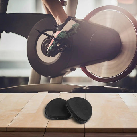 Comfy Armrest Pads For Indoor Cycling Bikes, 2 Piece EVA Cushioning System in black, displayed in front of an exercise bike wheel.