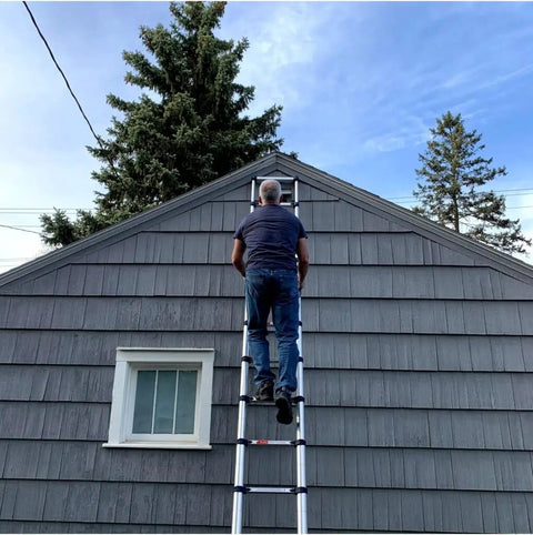 Man climbing Telescoping Ladder 15.5 Ft Reach 250 Lb Capacity With True Telescoping Tech Safety Closure And Individual Rung Locks No Pinch Close Foot Trigger Extension A Real Workhorse For Home Projects And Pro Jobs on gray house