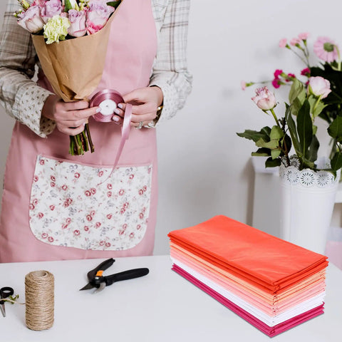 Person arranging flowers with Colorful Tissue Paper Pack 150 Sheets for Gift Wrapping and Crafting nearby on a table.