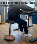 Person using Active Sitting Wobble Stool for Standing Desk, Anti Fatigue Stool, walnut finish, in home office setting.