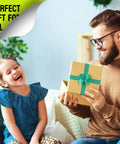Man giving a yellow gift box with turquoise ribbon to a young girl in a cozy living room setting.