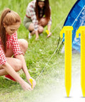 Two women securing a tent with bright yellow heavy duty plastic tent stakes 10 pack for camping beach canopy pegs.