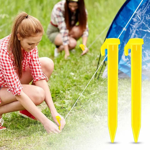 Two women securing a tent with bright yellow heavy duty plastic tent stakes 10 pack for camping beach canopy pegs.