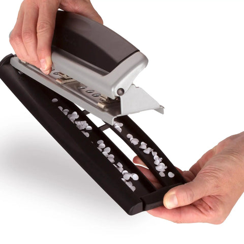 Hands holding Office Workhorse 3 Hole Paper Punch with adjustable settings, emptying punched paper confetti