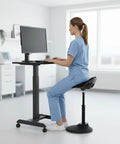 Woman using Comfy Ergonomic Sit Stand Stool For Standing Desk With Height Adjustment And 360 Degree Tilt Active Sitting Leaning Chair in a white office