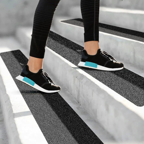 Person stepping on stairs with Non Slip Outdoor Stair Treads 8x30 Inch 12 Pack Black 80 Grit Grip Tape Heavy Duty Adhesive