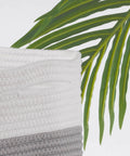 Close-up of Woven Rope Storage Baskets Set Of 3 For Books Toys Towels And Magazines, grey and white cotton rope detail with green foliage.