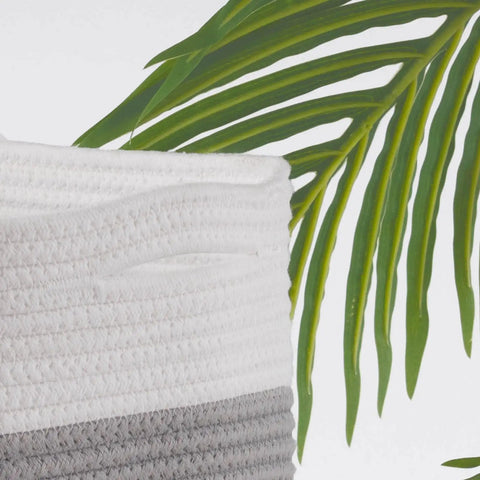 Close-up of Woven Rope Storage Baskets Set Of 3 For Books Toys Towels And Magazines, grey and white cotton rope detail with green foliage.