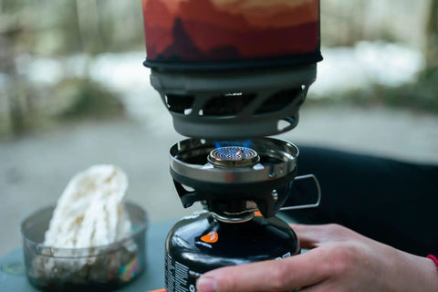 MiniMo Camping And Backpacking Stove Cooking System in use showing FluxRing Technology and adjustable heat control outdoors.