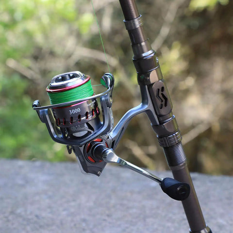 Close-up of a metallic reel and handle on a Telescopic Fishing Rod For Travel And Bass And Trout Angling With 24T Carbon Fiber Construction CNC Machined Reel Seat And Comfortable EVA Handle Silver 1.8m 5.9ft Portable Pole Saltwater Resistant Ceramic Ring Guides For Smooth Casting