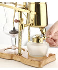 Top Shelf Siphon Coffee Maker Syphon Glass Brewer 4 Cup with gold finish and ergonomic handle in use for smooth brewing.