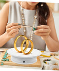 Autonomic Electric Rotating Display Stand For Jewelry Watches And Collectibles With Adjustable Speed showcases gold rings and jewelry crafting.