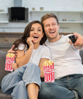 Couple enjoying movie night with popcorn in 100 Pack 1 Oz Popcorn Bags For Popcorn Machines And Movie Nights, Food Grade Paper Bags.