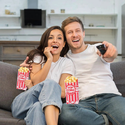 Couple enjoying movie night with popcorn in 100 Pack 1 Oz Popcorn Bags For Popcorn Machines And Movie Nights, Food Grade Paper Bags.