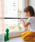 Child near a window secured with a Four Pack Sliding Door Security Bar With Rubber Tips Extendable Tension Rod Adjustable 15.7-27.6 in Black