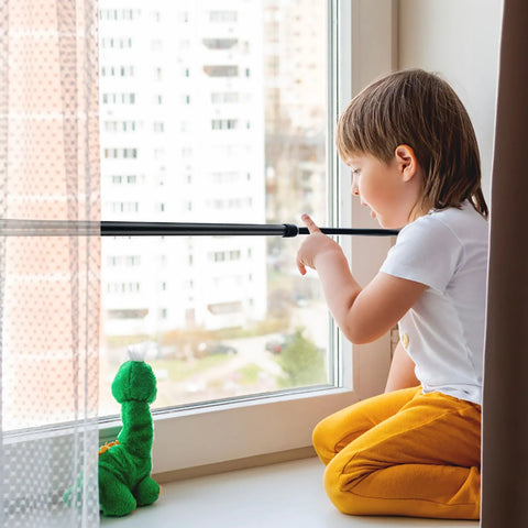 Child near a window secured with a Four Pack Sliding Door Security Bar With Rubber Tips Extendable Tension Rod Adjustable 15.7-27.6 in Black