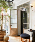 Antique Brass Double Sconce Wall Light With Clear 5.9 Inch Globe Shade in airy living room with glass doors and indoor plant