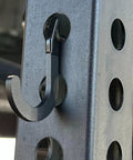 Close-up of black steel hook on power rack for DIY storage, used for hanging gym accessories, fits 1-inch hole-spaced racks.