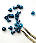 Twelve Piece Blue And Purple Titanium Triangle Screw Kit For Microtech Utx 85 And Ultratech Otf Knife Rigs on a light surface.