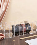 Top Shelf Slick Acrylic Belt Organizer With Removable Dust Cover Seven Compartment Clear Drawer Storage For Ties Belts Bow Tie Purse Socks, with three rolled belts visible.