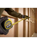 Person using Fatmax Tape Measure With Blade Armor And Dual Scale 8m Length, Mylar Coated Blade Delivers 10x Abrasion Resistance