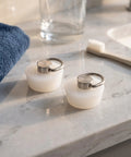 White Drain Stopper with Hanging Ring for Bathtub and Sink on marble countertop next to towel and toothbrush.