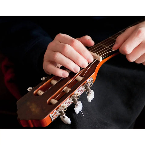 Person tuning guitar strings with All In One Guitar Repair Kit With Neck Rest Cradle And Pro Grade Gig Ready Work Mat For Studio And Shop